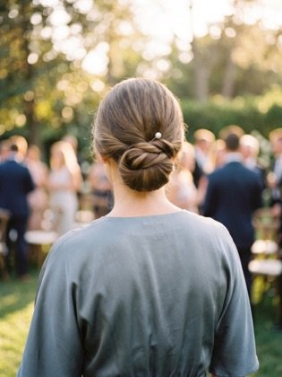 Gedrehter Chignon-Knoten im Nacken mit schlichter Perlennadel