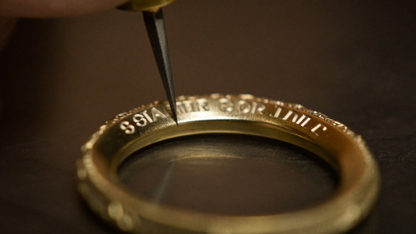 Goldschmied graviert einen Spruch in die Innenseite eines Traurings